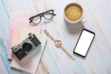 Açık ahşap arka planda gözlüklü ve cep telefonlu kompozisyon