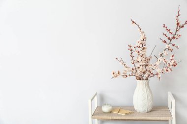 Odadaki raf ünitesinde çiçek açan güzel dalları olan vazo.