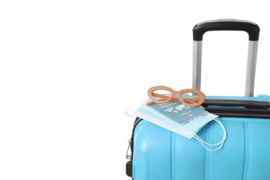 Beyaz arka planda bağışıklık pasaport, tıbbi maskeler ve güneş gözlüğü olan bavullar.
