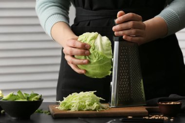 Kadın aşçı mutfaktaki masada lezzetli lahana salatası pişiriyor.