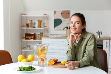 Genç bayan evde taze limonata yapıyor.