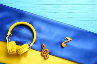 Renkli ahşap arka planda Ukrayna bayrağı olan müzik notaları ve kulaklıklar
