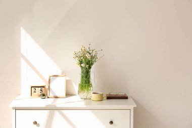 Lambanın yanındaki rafta papatya çayı ve dekor olan vazo.