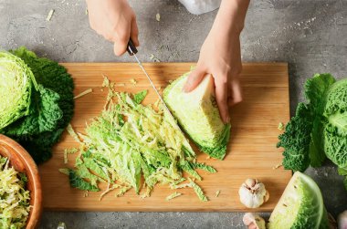 Kadın arka planda taze savoy lahanası kesiyor.