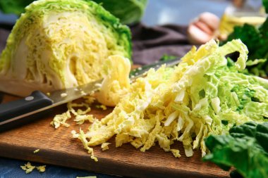 Renkli arka planda kesilmiş savoy lahanası yığını olan tahta, yakın plan.