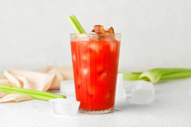 Hafif arka planda domuz pastırması ve kereviz ile süslenmiş bir bardak Bloody Mary kokteyli.