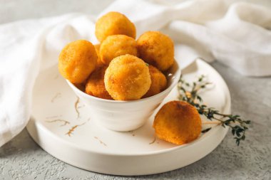 Arka planda kızarmış patates topları olan bir kase.