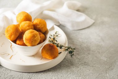 Arka planda kızarmış patates topları olan bir kase.