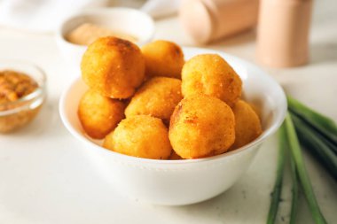 Hafif arka planda kızarmış patates topları olan bir kase.