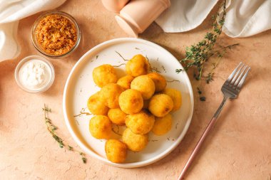 Arka planda kızarmış patates topları olan tabak.