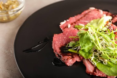 Arkaplanda lezzetli bir carpaccio tabağı, yakın plan.