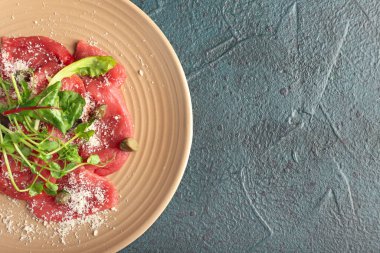 Koyu arkaplanda lezzetli dana eti ve carpaccio tabağı.