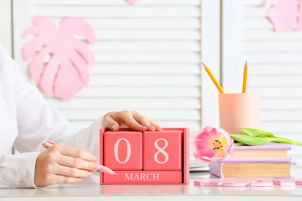 携带日期为3月8日的立方体日历的妇女在房间的桌子上 — 图库照片