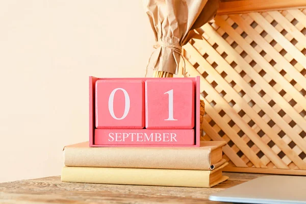 Cube calendar with date SEPTEMBER 1 and books on table in room, closeup