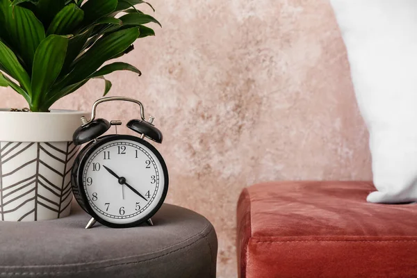目覚まし時計と観葉植物の近くにPouf色の壁 — ストック写真