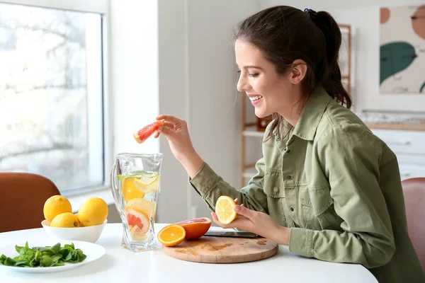 在家里做新鲜柠檬水的年轻女人 — 图库照片