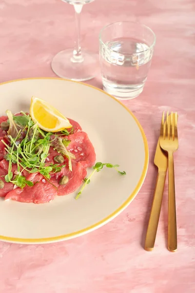 Bord Met Lekker Kalfsvlees Carpaccio Glas Water Kleur Achtergrond — Stockfoto