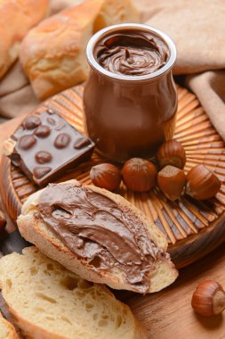 Lezzetli çikolata ezmeli kavanoz ve ahşap arka planda fındık.