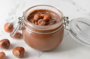 Lezzetli çikolata ezmeli kavanoz ve arka planda fındık.