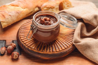 Lezzetli çikolata ezmeli kavanoz ve ahşap arka planda fındık.