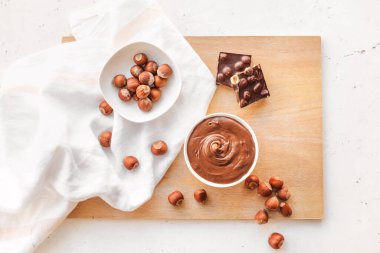 Tatlı çikolata ezmeli kase ve arka planda fındık.