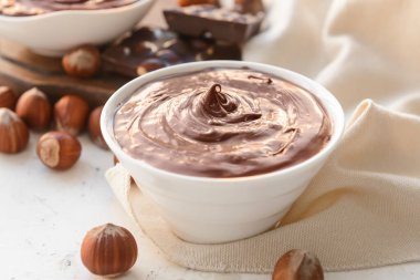 Tatlı çikolata ezmeli kase ve arka planda fındık.