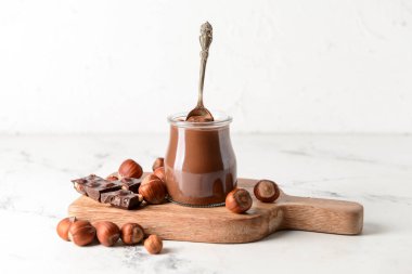 Lezzetli çikolata ezmeli kavanoz ve arka planda fındık.