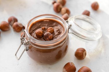 Lezzetli çikolata ezmeli kavanoz ve arka planda fındık.