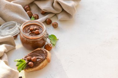 Lezzetli çikolata ezmeli kavanoz ve arka planda fındık.