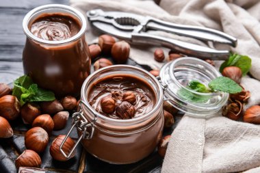 Lezzetli çikolata ezmeli kompozisyon ve koyu ahşap arka planda fındıklar.