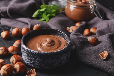 Lezzetli çikolata ezmeli kase ve koyu arkaplanda fındık.