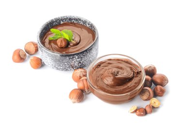 Lezzetli çikolata ezmeli kaseler ve beyaz arka planda fındıklar.