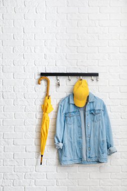 Tuğla duvarda asılı giysiler ve aksesuarlarla dizilin.