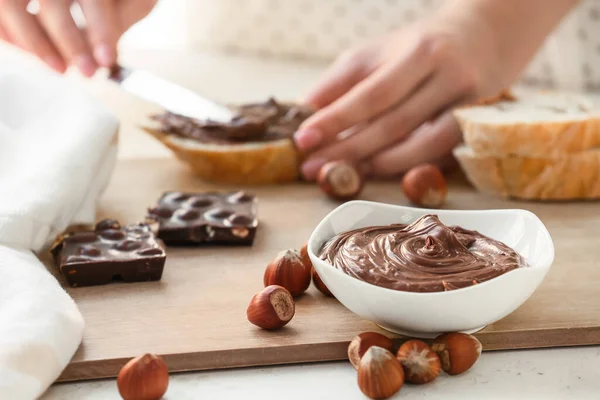 Woman Spreading Tasty Chocolate Paste Hazelnuts Bread Kitchen — Stock Photo, Image