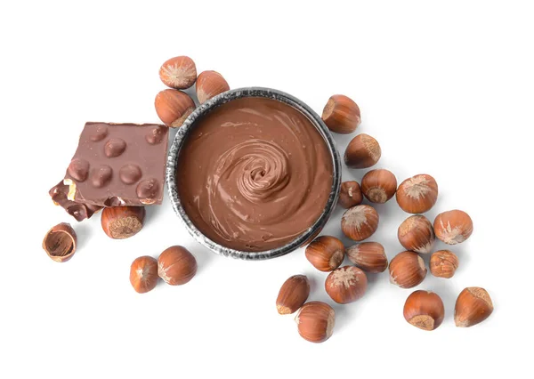 Bowl with tasty chocolate paste and hazelnuts on white background