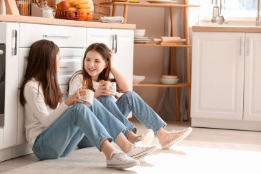 Mutfakta yerde oturan tatlı ikiz kızlar.