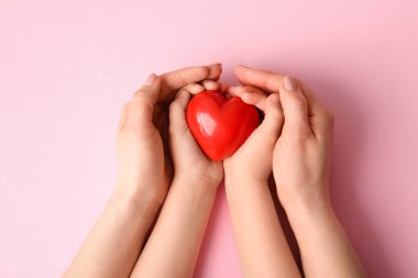 Renkli arka planda kırmızı kalpli kadın ve çocuğun elleri