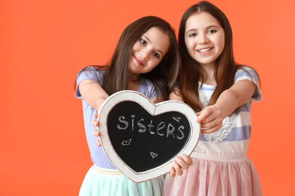 かわいいです双子の女の子とボードとともに単語姉妹上の色の背景 — ストック写真