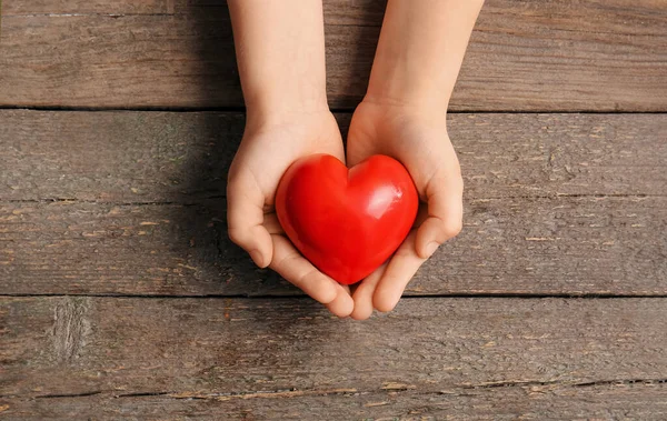 Mani Bambino Con Cuore Rosso Sfondo Legno — Foto Stock