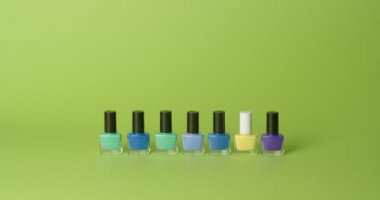 Different nail polishes on color background, video with stop motion effect