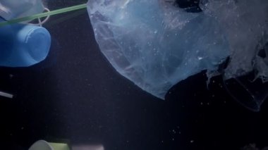 Garbage in water against dark background. Ecology concept