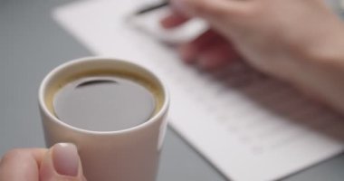Kahve içen ve yapılacaklar listesini kontrol eden kadın, yakın plan.