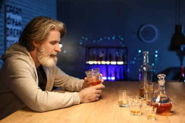 Senior man with glass of drink late in evening at home