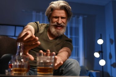 Senior man refusing to drink whiskey late in evening at home