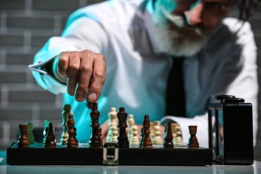 Senior man playing chess at table, closeup