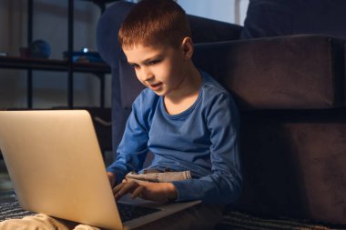 Küçük çocuk akşam geç saatlerde internette ödev yapıyor.