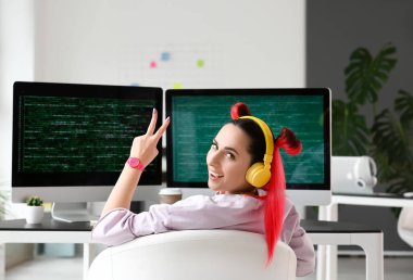 Kadın programcı ofiste zafer jesti gösteriyor.