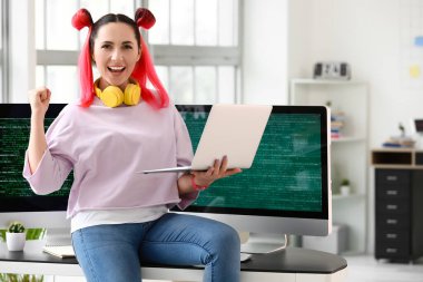 Ofiste dizüstü bilgisayarla çalışan mutlu kadın programcı.