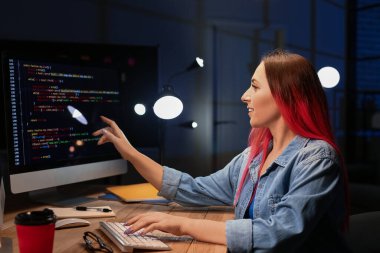 Geceleri bilgisayarla çalışan kadın programcı.