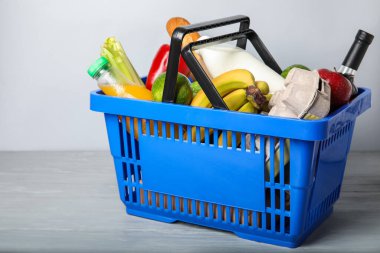 Işık duvarının yanındaki masada yiyecek olan alışveriş sepeti.